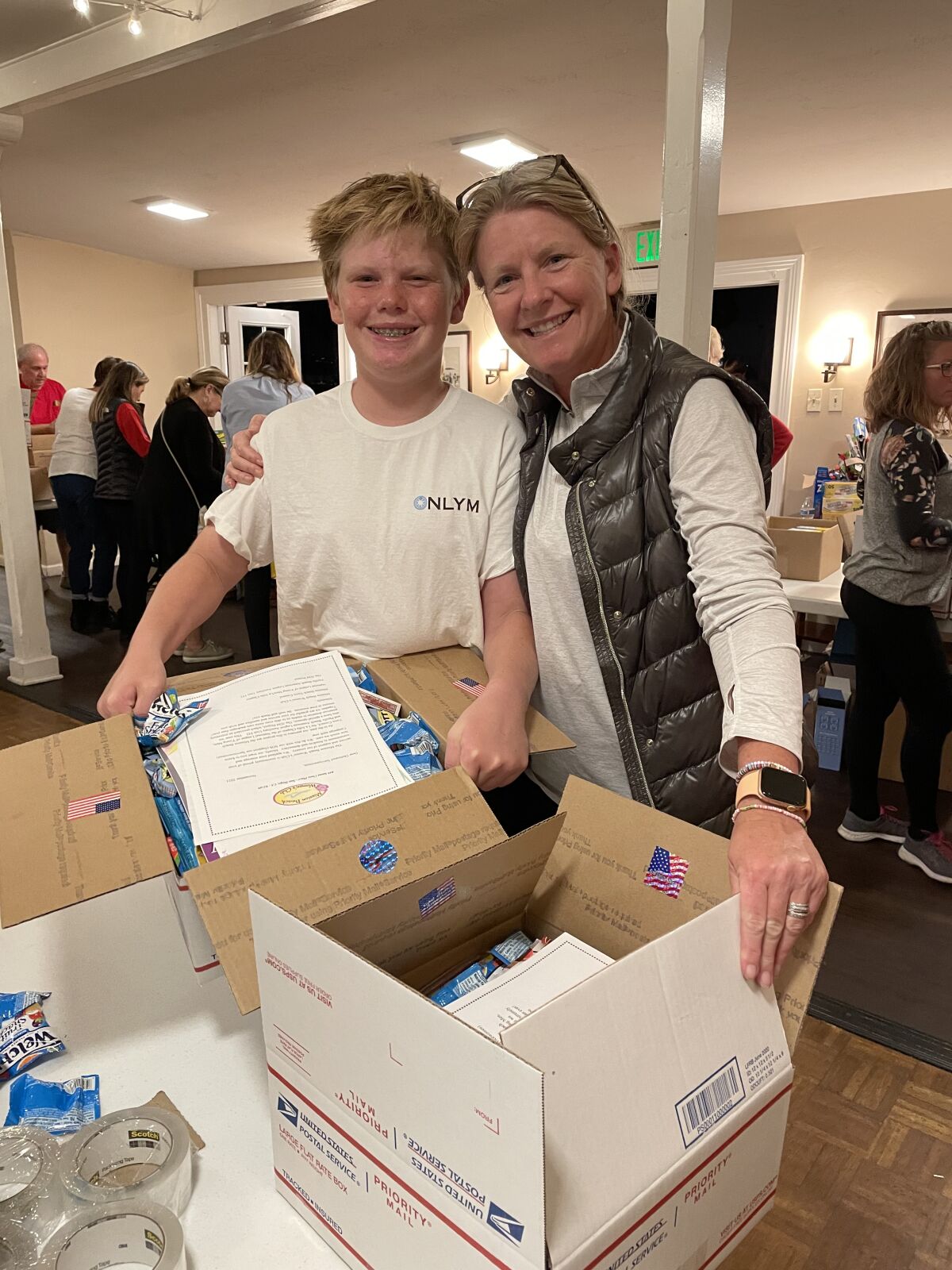 La Jolla High freshman Cooper Smith and his mother, Adi, show boxes of personal items to be shipped to military servicewomen.