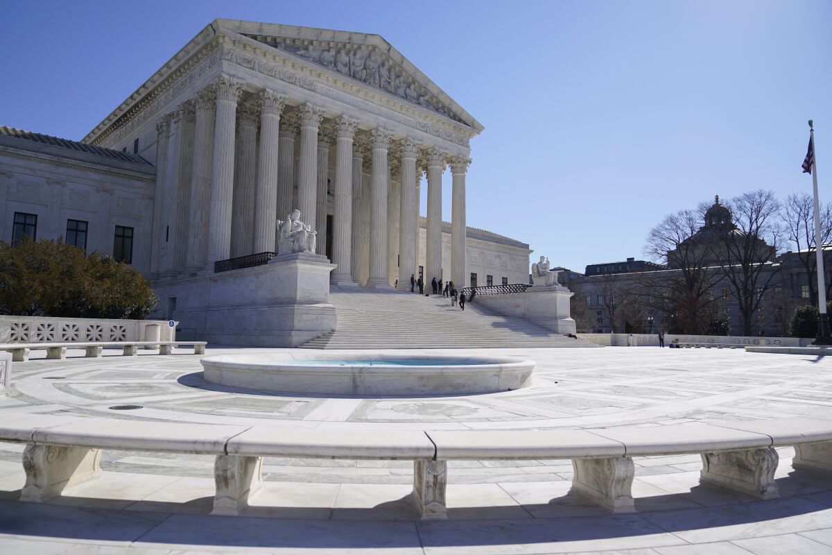 People stand on the steps of the U.S. Supreme Court on Friday, Feb.11, 2022, in Washington. (AP Photo/Mariam Zuhaib)