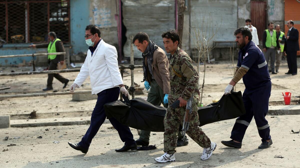 Security personnel carry a body away from a Kabul checkpoint that was attacked by a suicide bomber on March 9.