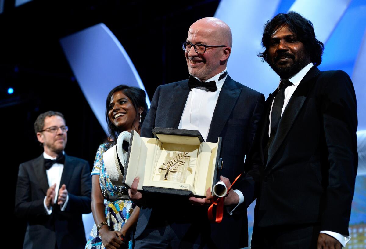 Director Jacques Audiard holds his prize, flanked by "Dheepan" actress Kalieaswari Srinivasan and actor Jesuthasan Antonythasan.