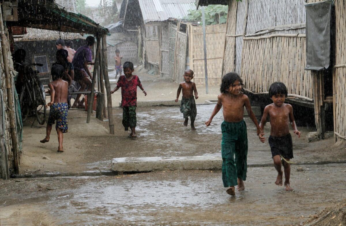 Rohingya children play during rain at an Internally Displaced Persons camp near Sittwe of Rakhine State, western Myanmar, 22 March 2016.