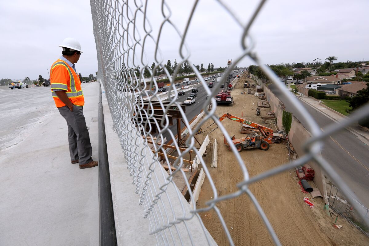 Wahed Ibrahim from OC 405 Partners looks over the freeway construction site while standing on the Slater Avenue bridge in Fountain Valley, which will reopen Thursday night. The bridge has four lanes, sidewalks and bike lanes on both sides.