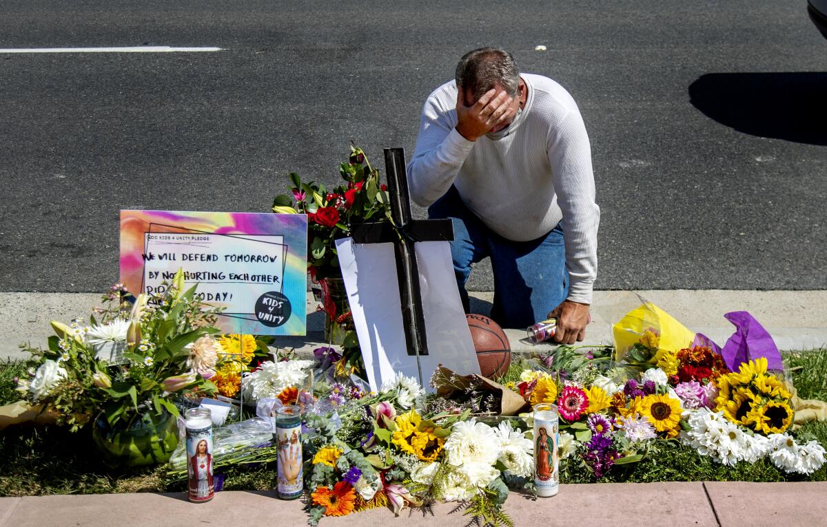 A man kneels at a memorial for Kurt Andras Reinhold