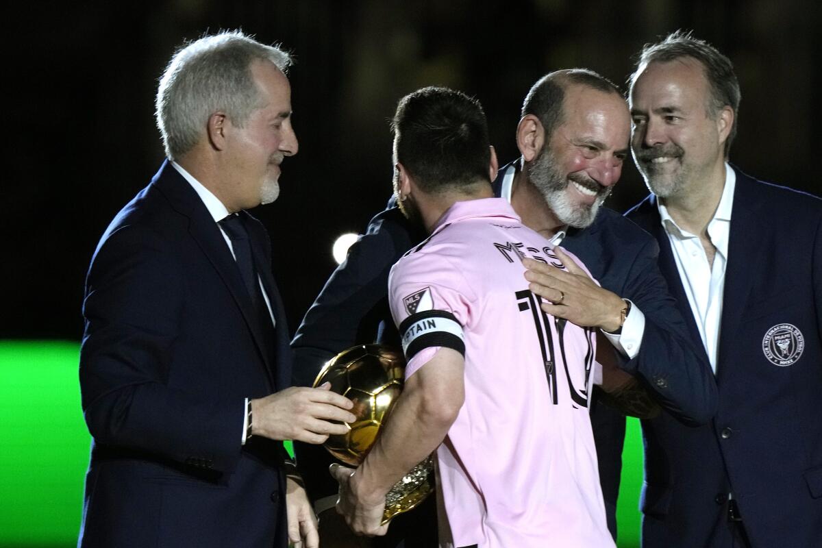 Inter Miami forward Lionel Messi is hugged by MLS Commissioner Don Garber, center right, during a ceremony honoring Messi.