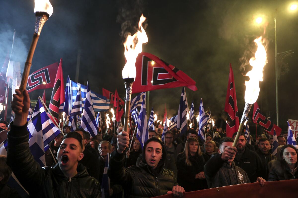 FILE - In this Saturday, Feb. 2, 2019 file photo, supporters of Greece's extreme right Golden Dawn raise torches during a rally commemorating a 1996 military incident which cost the lives of three Greek navy officers and brought Greece and Turkey to the brink of war, in Athens. Greek police officials they are planning to deploy about 2,000 officers around Athens as the leadership of the extreme right group Golden Dawn faces a landmark criminal trial verdict. Eighteen former lawmakers from the party founded in the 1980s as a neo-Nazi organization are among 69 defendants who have been on trial for the past five years. The verdict is expected Wednesday Oct. 7, 2020. (AP Photo/Yorgos Karahalis, File)