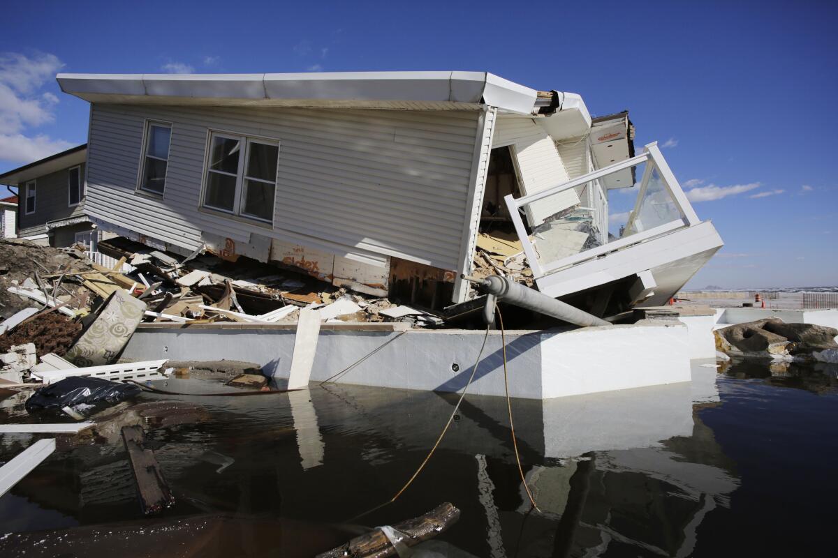 A very damaged beachfront house sits among its wreckage in Queens 