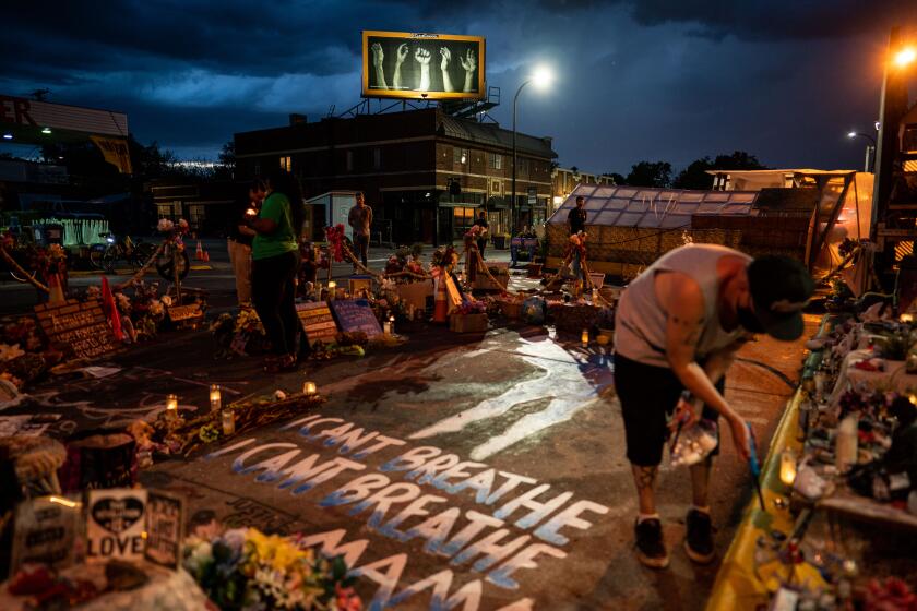 MINNEAPOLIS, MN - MAY 24: Billy Briggs, who lives right around the corner from the George Floyd Memorial Square lights candles around the memorial where the late Floyd died, on Monday, May 24, 2021 in Minneapolis, MN. (Kent Nishimura / Los Angeles Times)