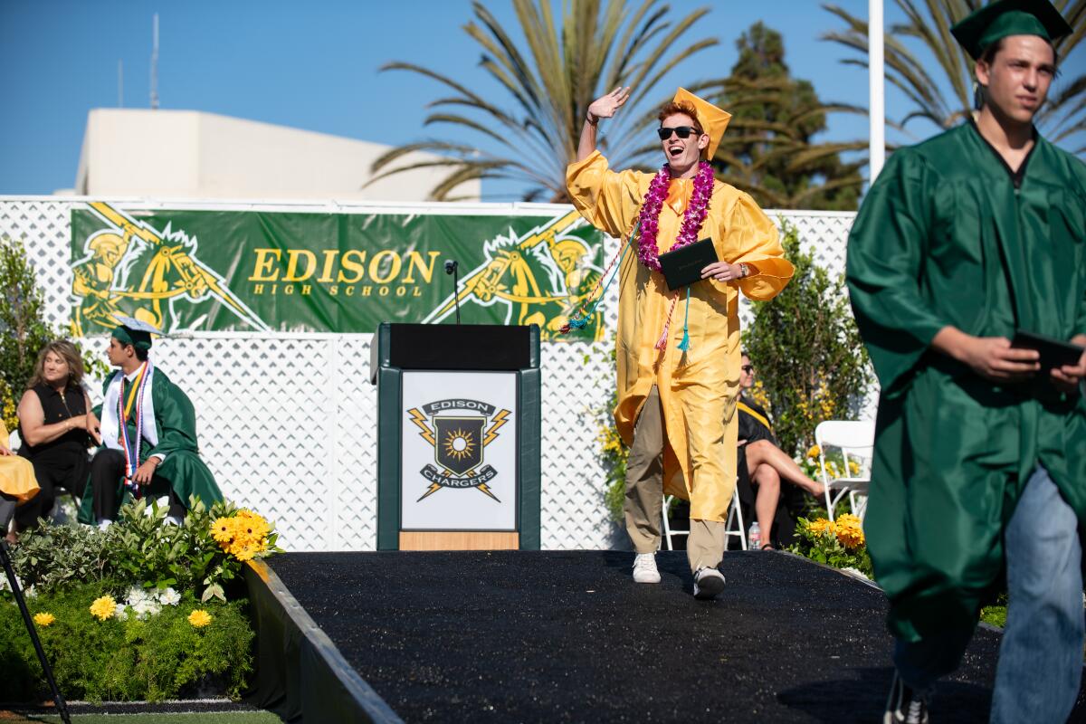 An Edison High senior waves to his parents in the stands during the Chargers' graduation ceremony on Thursday.
