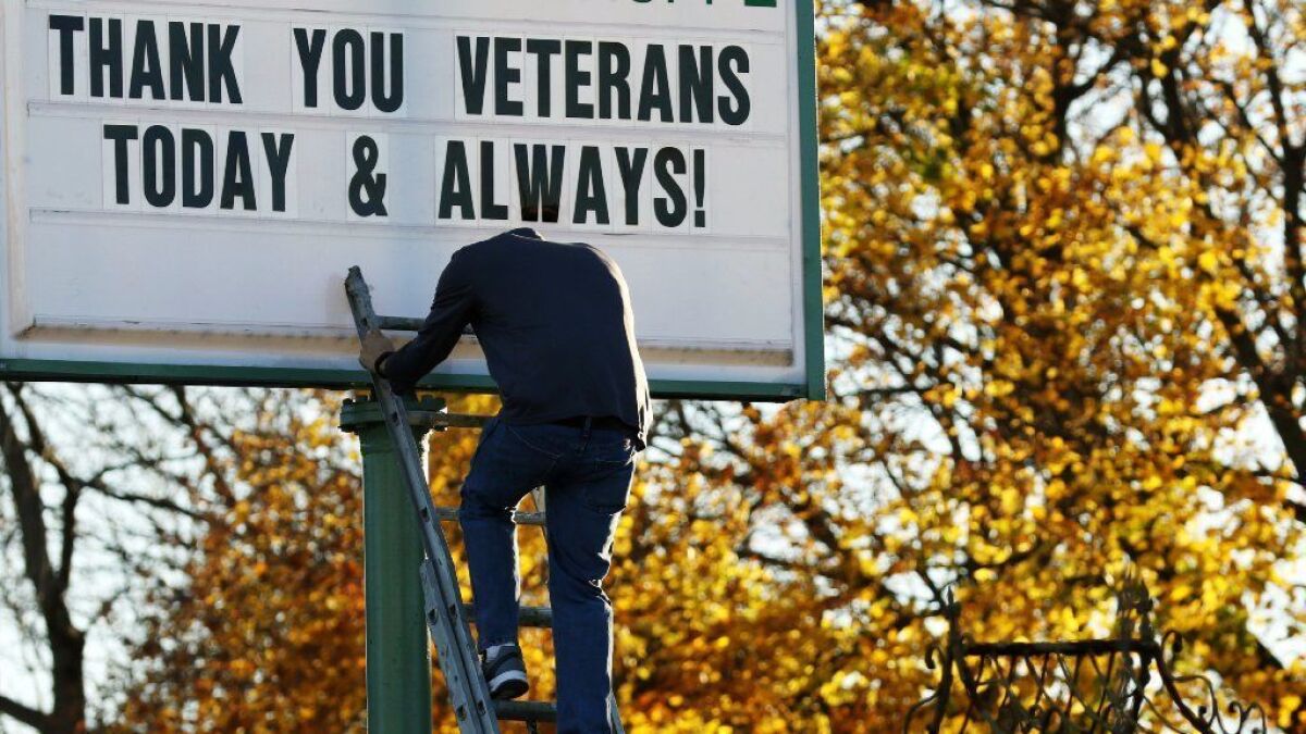 A man climbs down a ladder to get more letters to complete the message for veterans.