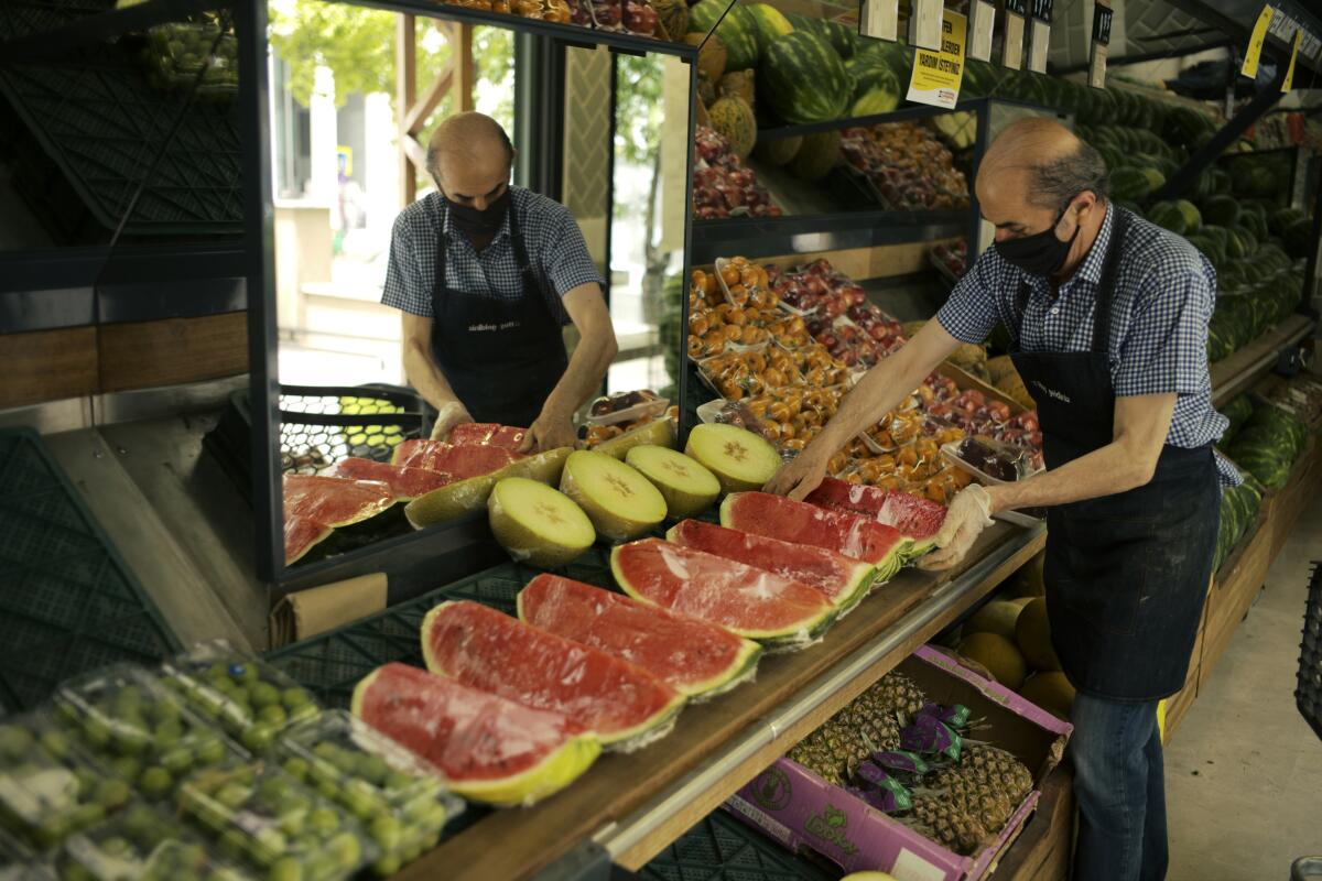 A worker arranges fruit for sale a food market