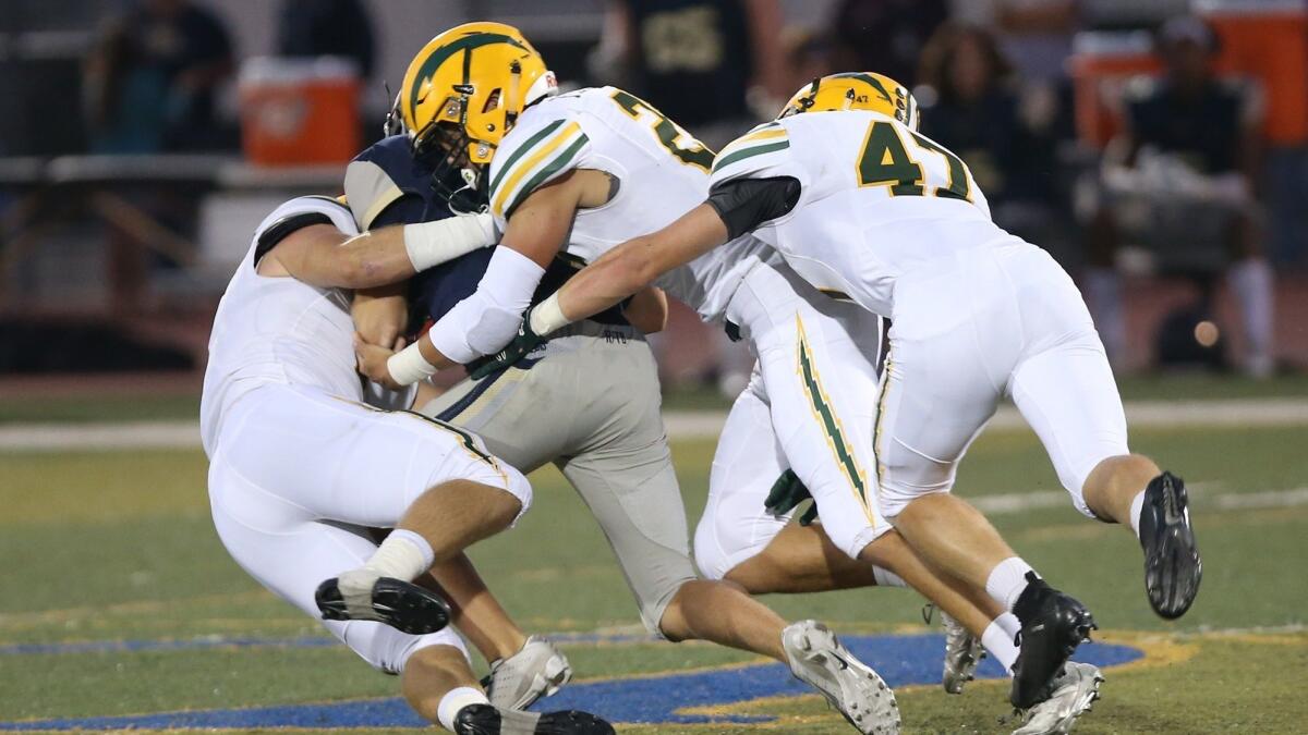 Edison High's Cameron Eden, left, Mike Walters, middle, and Bryce Gilbert, right, take down San Juan Hills quarterback Jake Carreon in a nonleague football game on Friday.