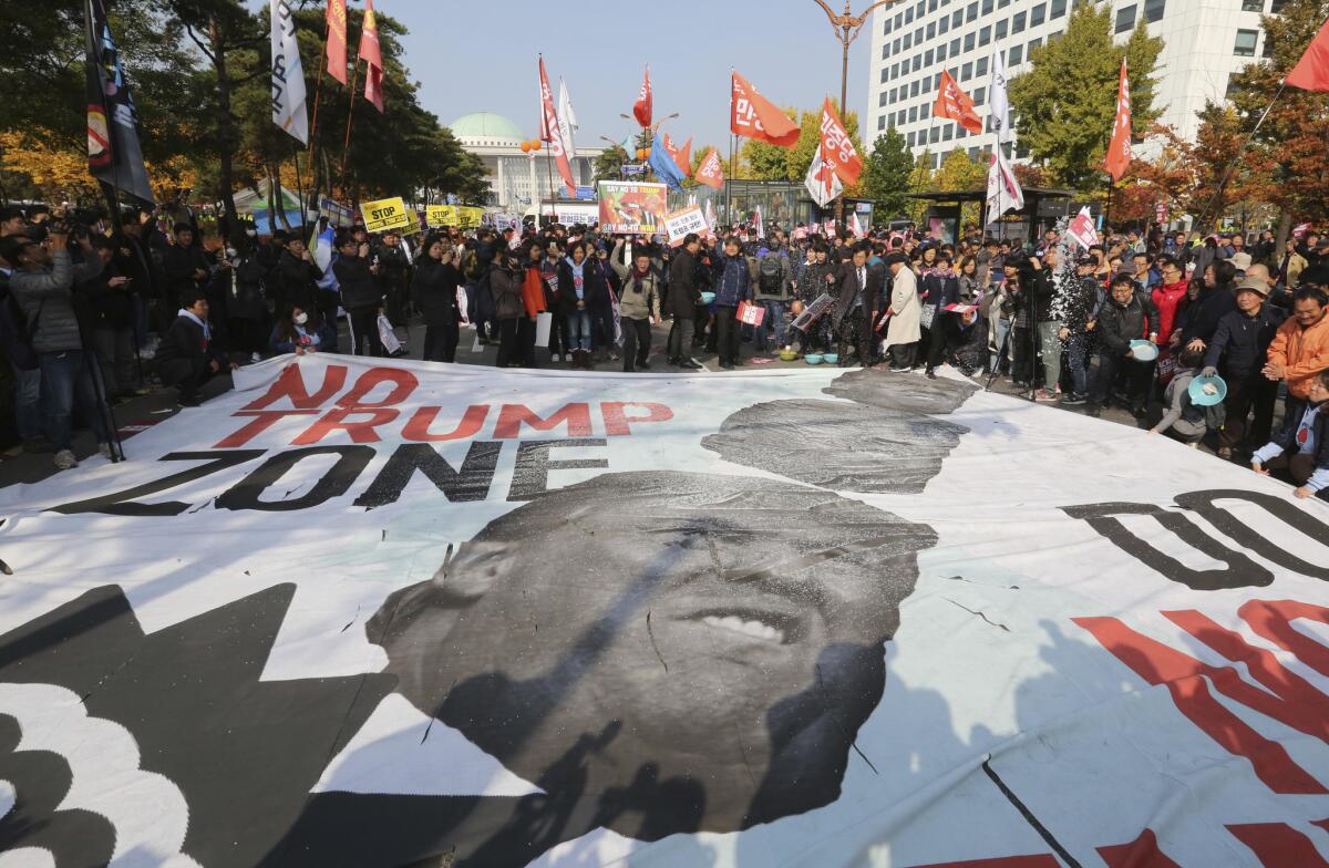 Protesters hurl salt at a banner showing images of President Trump during a rally against his visit in front of the National Assembly in Seoul in November 2017.