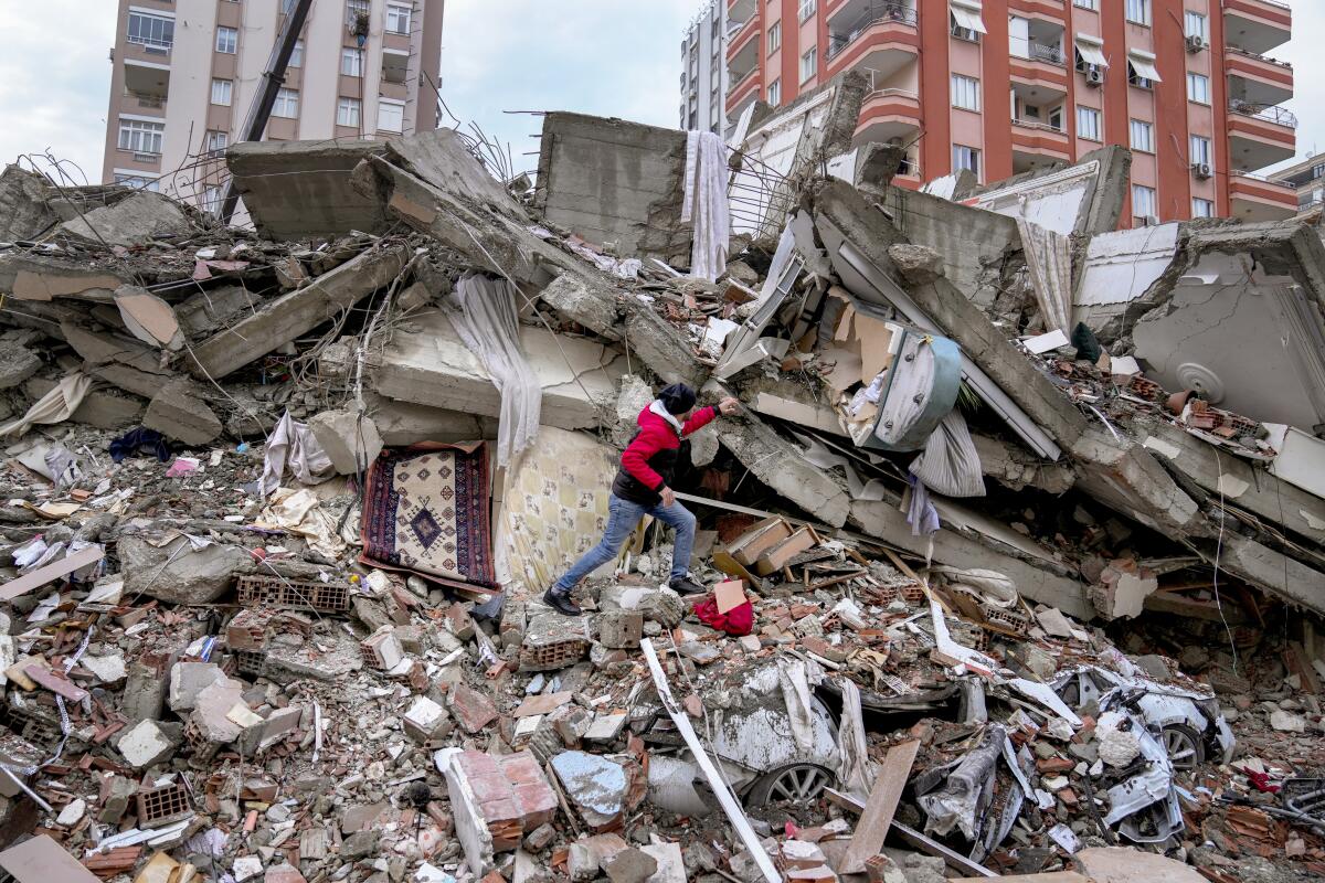 A man walks among rubble as he searches for people in a destroyed building in Adana, Turkey, on Monday.