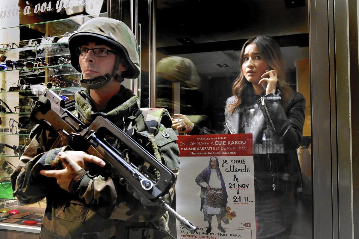 A shopkeeper stays inside her store as soldiers guard the street in Paris on Nov. 15, amid rumors of another terrorist attack. The rumors proved false.