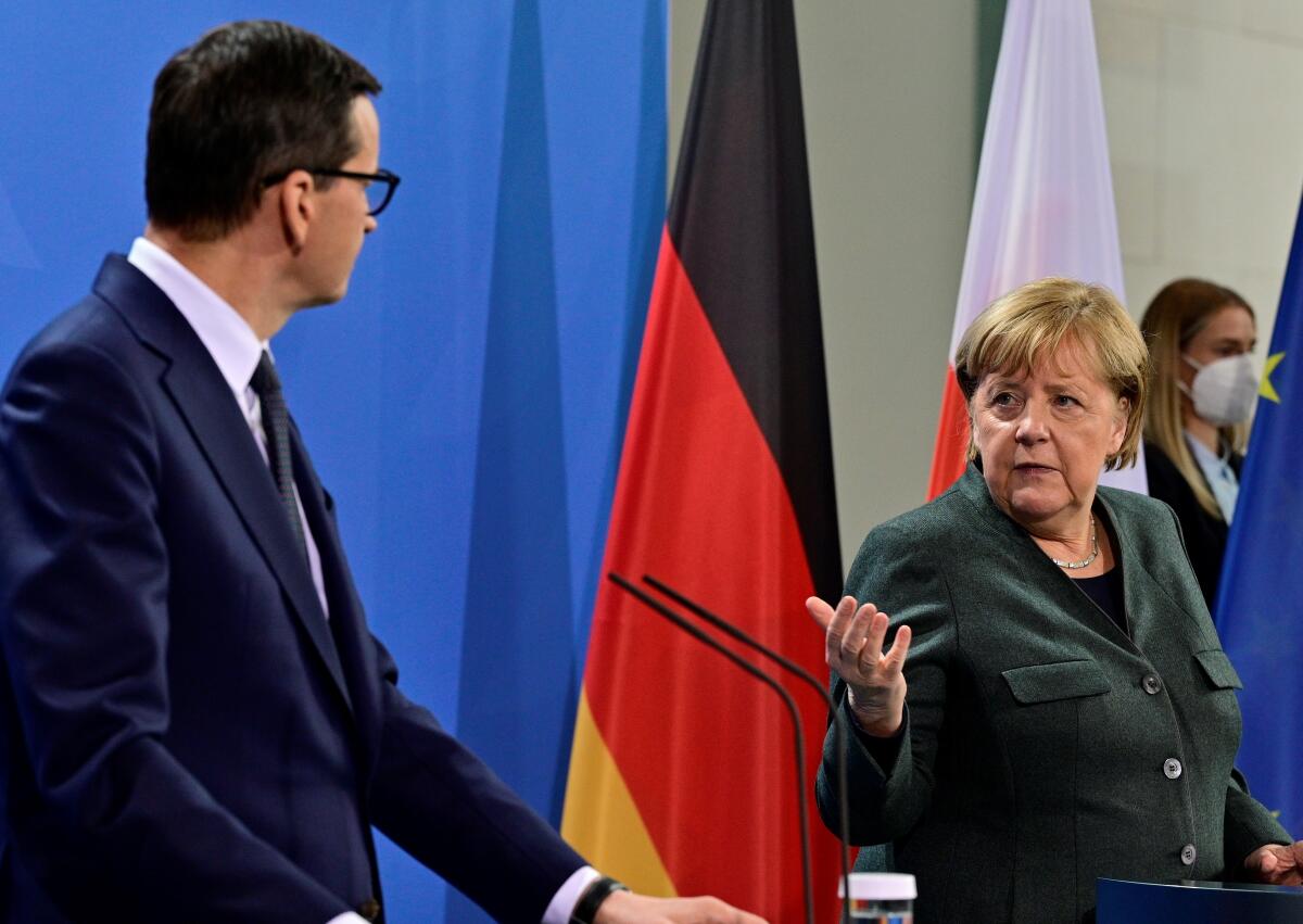 German Chancellor Angela Merkel, right, and Prime Minister of Poland Mateusz Morawiecki brief the media after talks at the chancellery in Berlin, Germany, Thursday, Nov. 25, 2021. (John MacDougall / Pool Photo via AP)