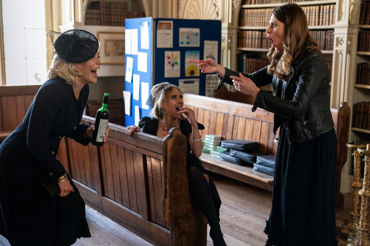 Three women share wine and laugh while attending a funeral in a scene from "Ted Lasso."
