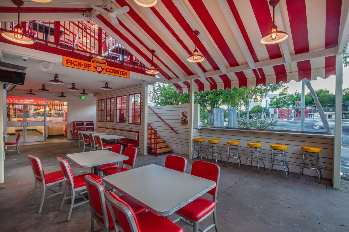 Tables and bar seating under a red and white awning