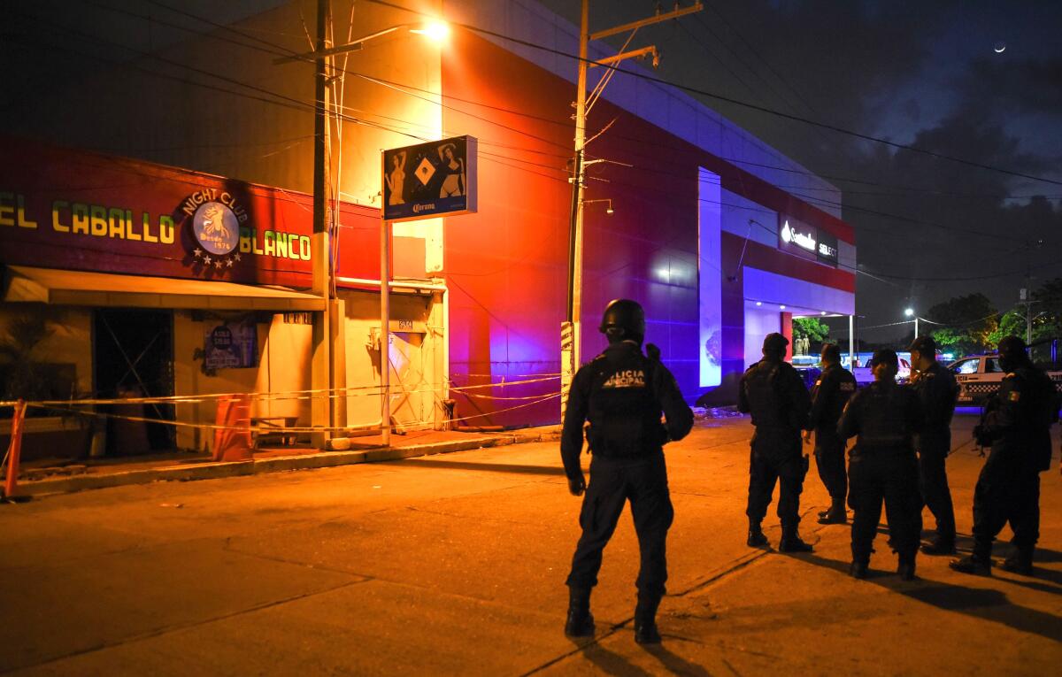 Police officers stand guard outside Caballo Blanco (White Horse) bar where 27 people were killed by a fire