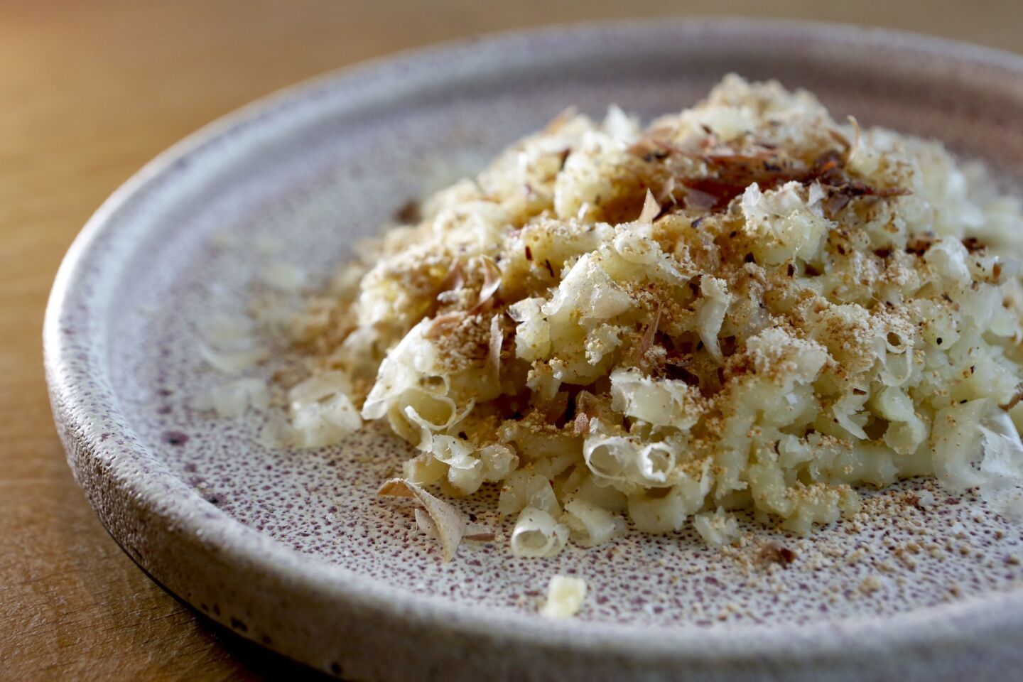 Chef Ludovic Lefebvre makes a main dish out of slightly undercooked Weiser Family Farms potatoes passed through a ricer directly onto a plate of brown butter, onion soubise and Salers cheese from the Auvergne, then sprinkled with dried Japanese bonito flakes.