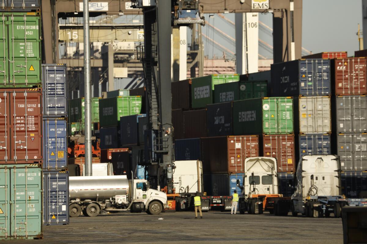 Container ships are unloaded at the Port of Los Angeles as trucks line up to receive containers.