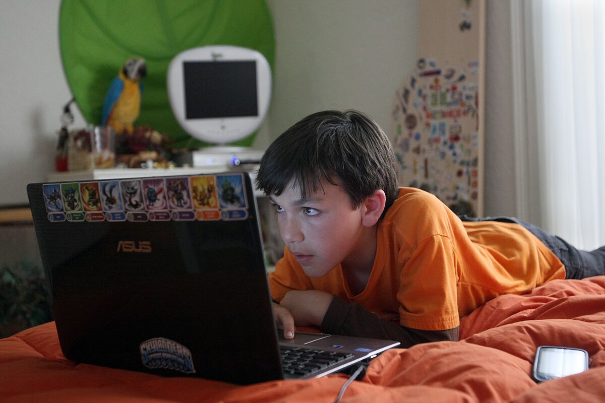 Friedman, Gary -- B582130423Z.1 LOS ANGELES, CALIF. - MAY 31, 2012: Cole Chanin-Hassman, 10, looks at a computer game call Minecraft on his laptop in his Brentwood home on May 31, 2012. Minecraft is a game which teaches Cole to build cities and other programs. Cole uses multiple devices such as the computer, phone, tv X-Box, Ipad, sometimes at one time and other times separate. (Gary Friedman/Los Angeles Times)