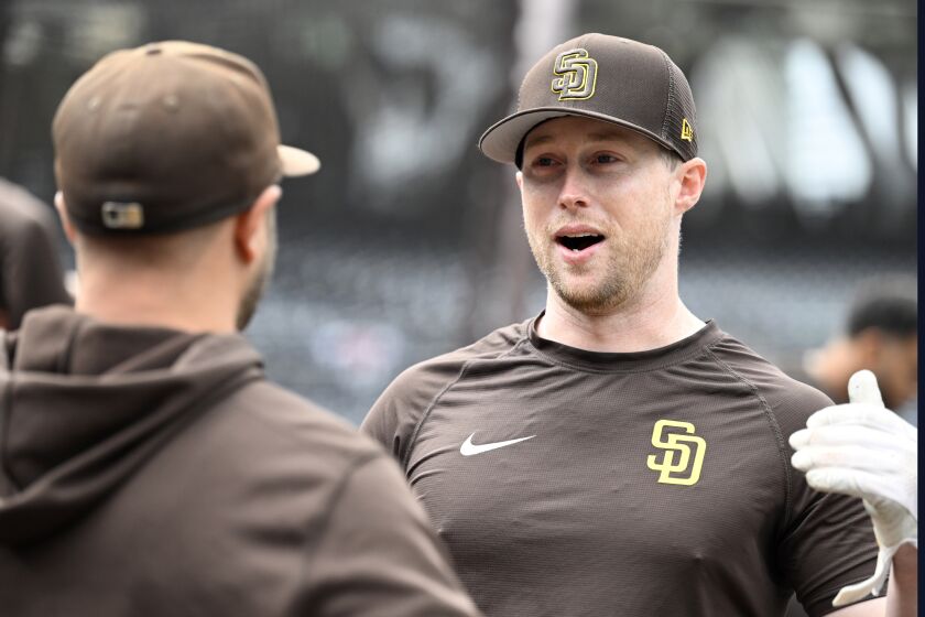 El primera base de los Padres de San Diego Jake Cronenworth habla con su compañero durante el calentamiento antes del juego de inicio de temporada ante los Rockies de Colorado el jueves 30 de marzo del 2023. (AP Foto/Alex Gallardo)