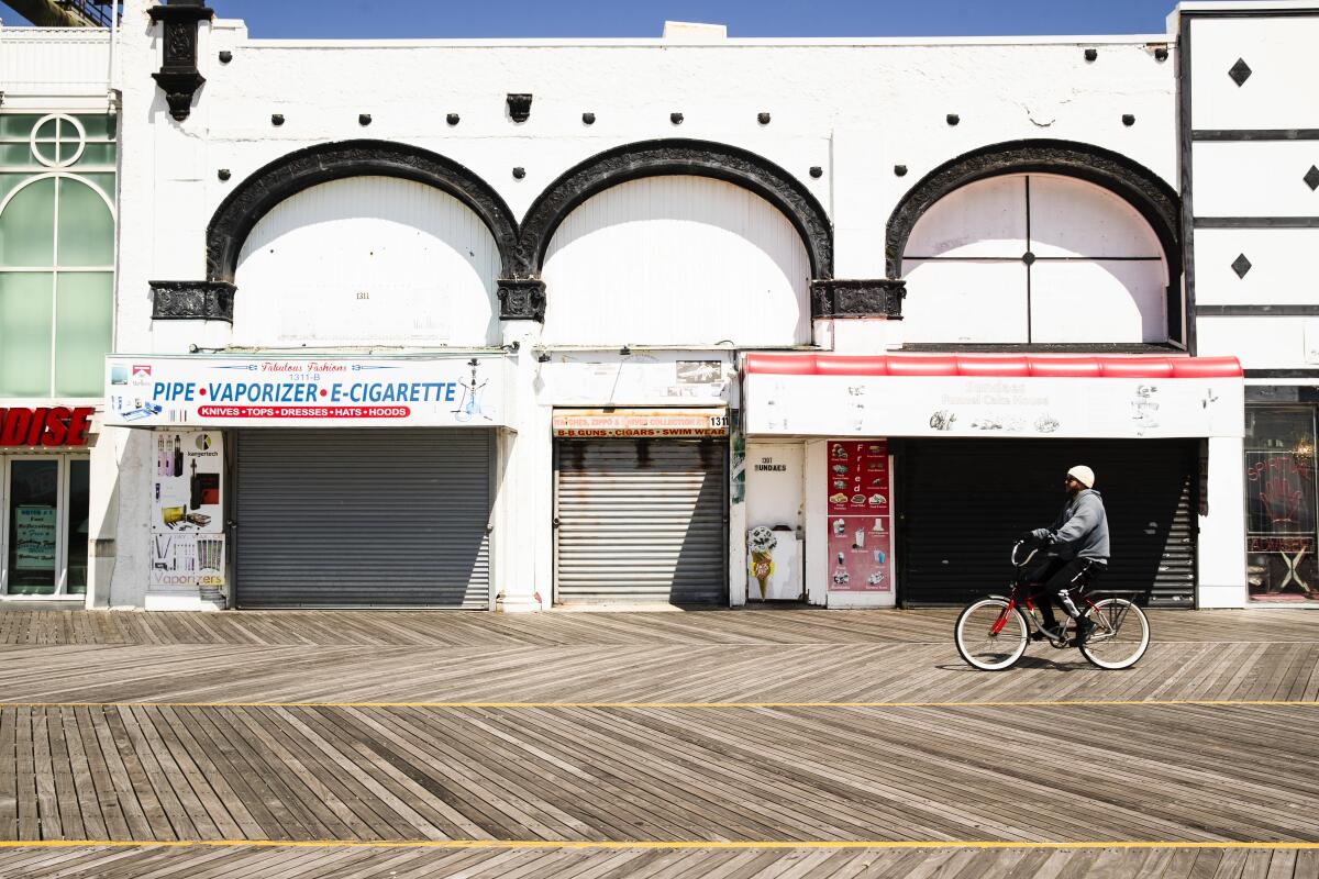 A cyclist rides past shuttered businesses during the coronavirus outbreak on the boardwalk in Atlantic City, N.J.
