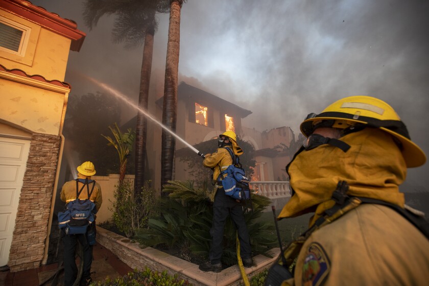 Firefighters soak a home to protect it.