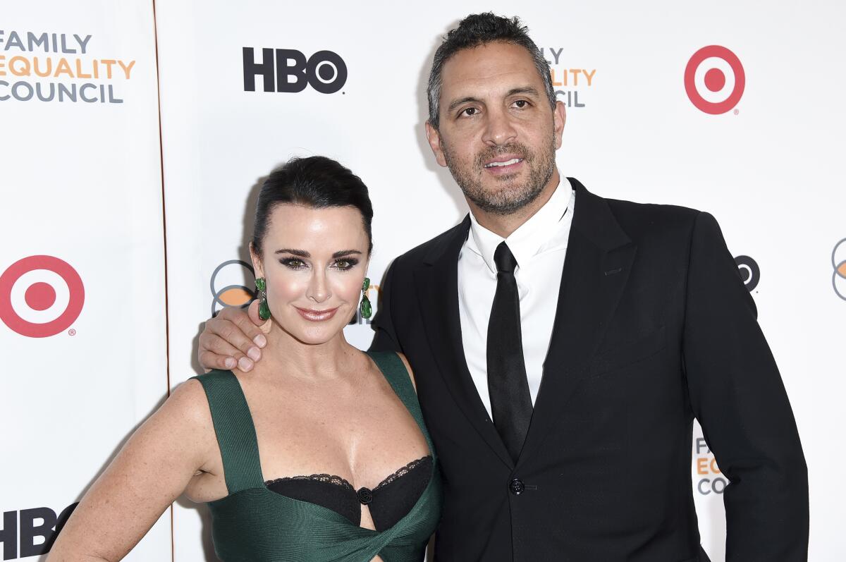 Kyle Richards and Mauricio Umansky stand together in formal attire against a white backdrop.