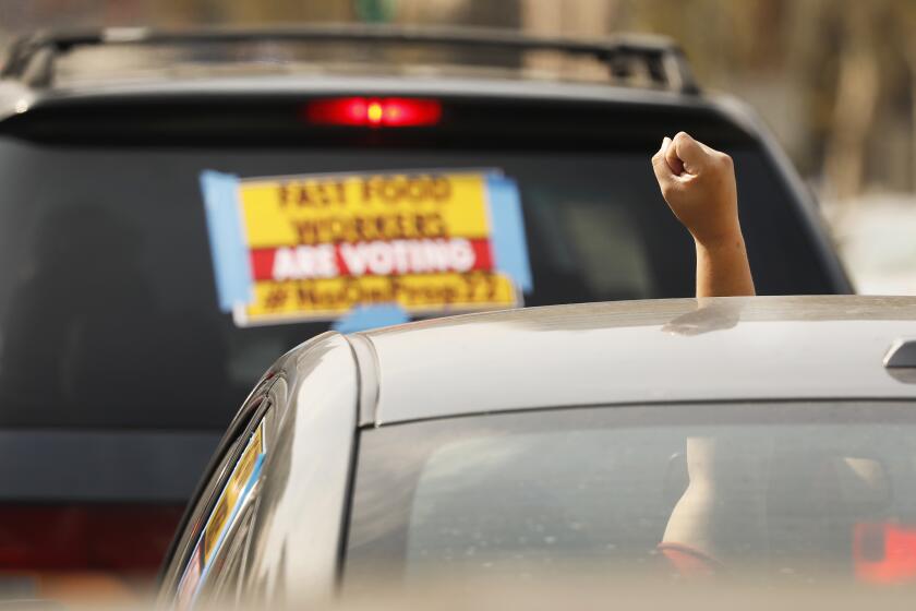 LOS ANGELES, CA - OCTOBER 08: Rideshare driver M.J. raises her fist in support as app based gig workers held a driving demonstration with 60-70 vehicles blocking Spring Street in front of Los Angeles City Hall urging voters to vote no on Proposition 22, a November ballot measure that would classify app-based drivers as independent contractors and not employees or agents, providing them with an exemption from California's AB 5. The action is part of a call for stronger workers' rights organized by the Mobile Workers Alliance with 19,000 drivers in Southern California and over 40,000 in all of California. Los Angeles on Thursday, Oct. 8, 2020 in Los Angeles, CA. (Al Seib / Los Angeles Times