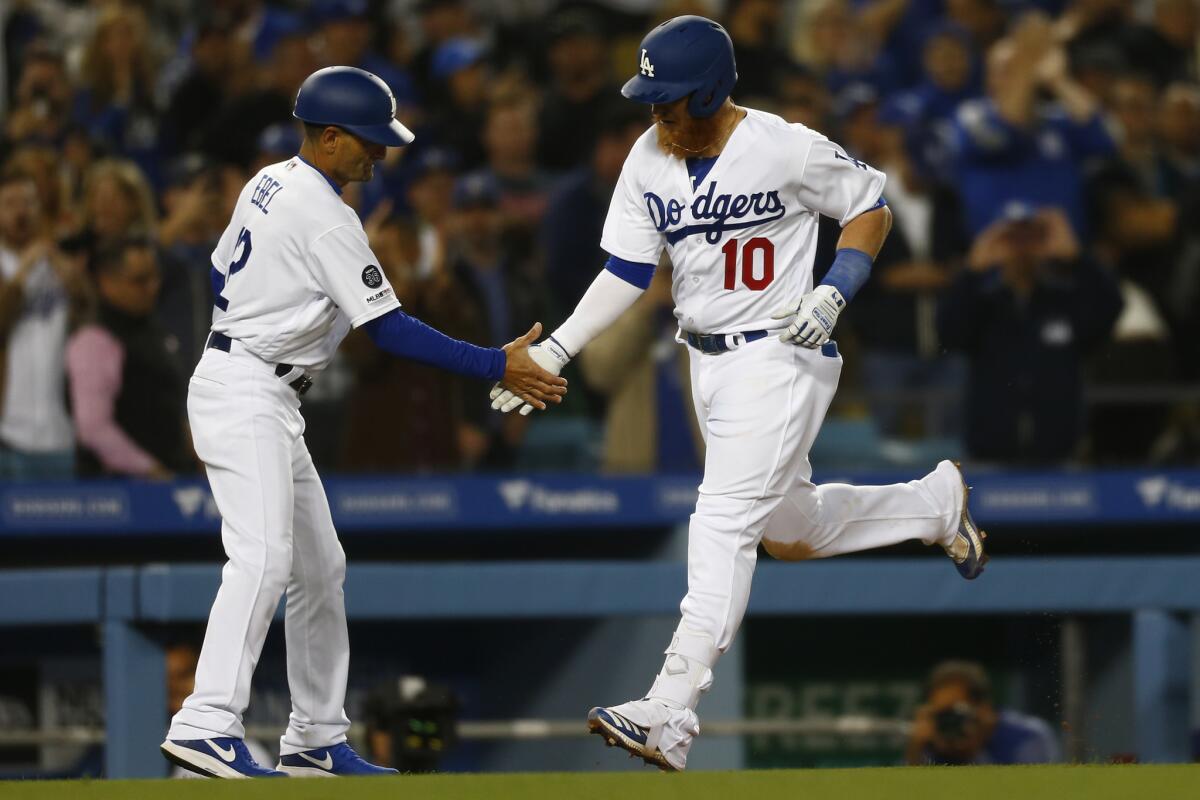 Dodgers third base coach Dino Ebel (12) congratulates third baseman Justin Turner (10) on Turner's two-run home run against the Atlanta Braves during the game at Dodger Stadium on Wednesday.