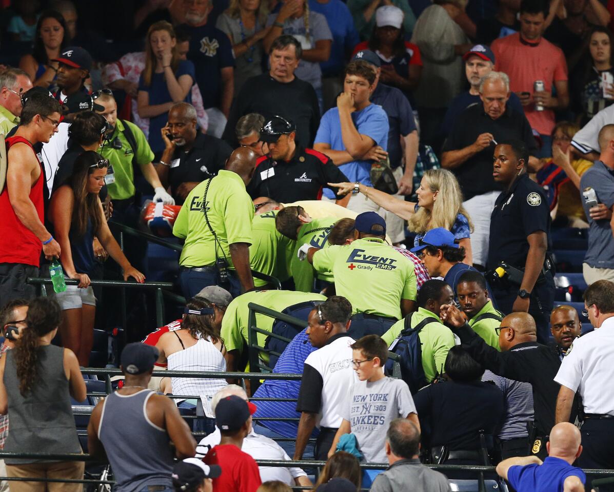 Fans look on as emergency medical personnel work on a fan who fell from an upper deck at Turner Field during a baseball game between New York Yankees and Atlanta BravesSaturday, Aug. 29, 2015, in Atlanta.