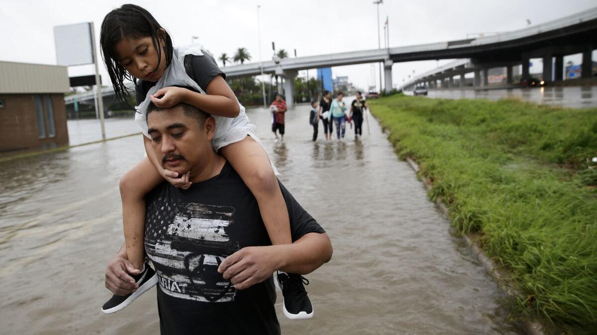 Jesus Nunez carries his daughter Genesis, 6, as he and numerous family members flee their flooded home in Houston, Texas.