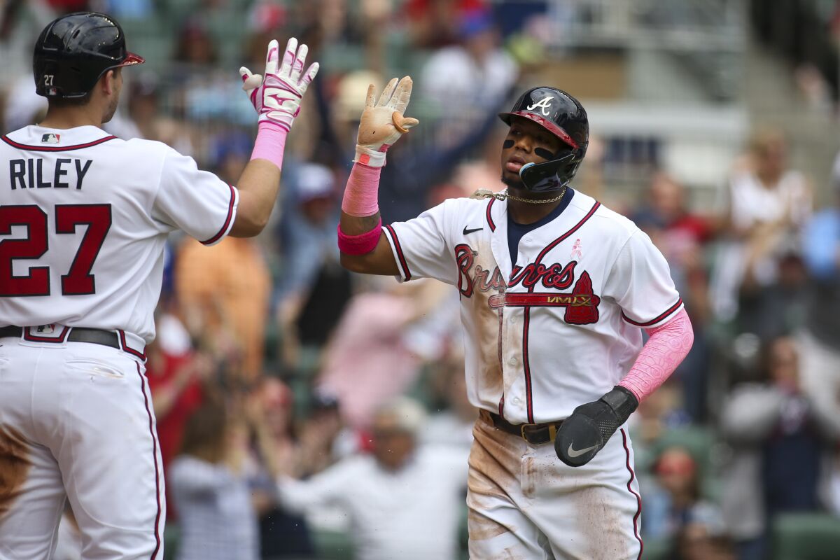 Atlanta Braves right fielder Ronald Acuna Jr., right, celebrates after scoring with third baseman Austin Riley (27) in the second inning of a baseball game against the Milwaukee Brewers, Sunday, May 8, 2022, in Atlanta. (AP Photo/Brett Davis)