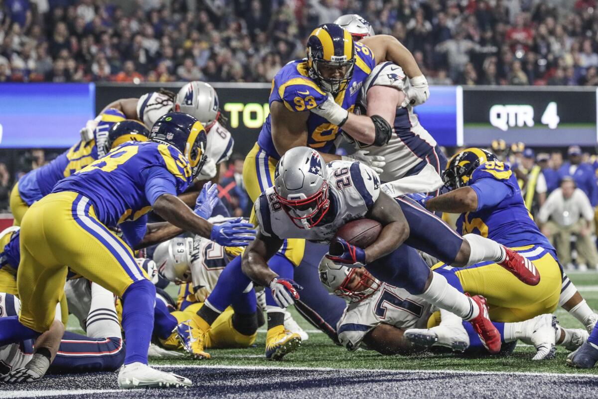 New England Patriots and Los Angeles Rams football players on the field at the 2019 Super Bowl in Atlanta.