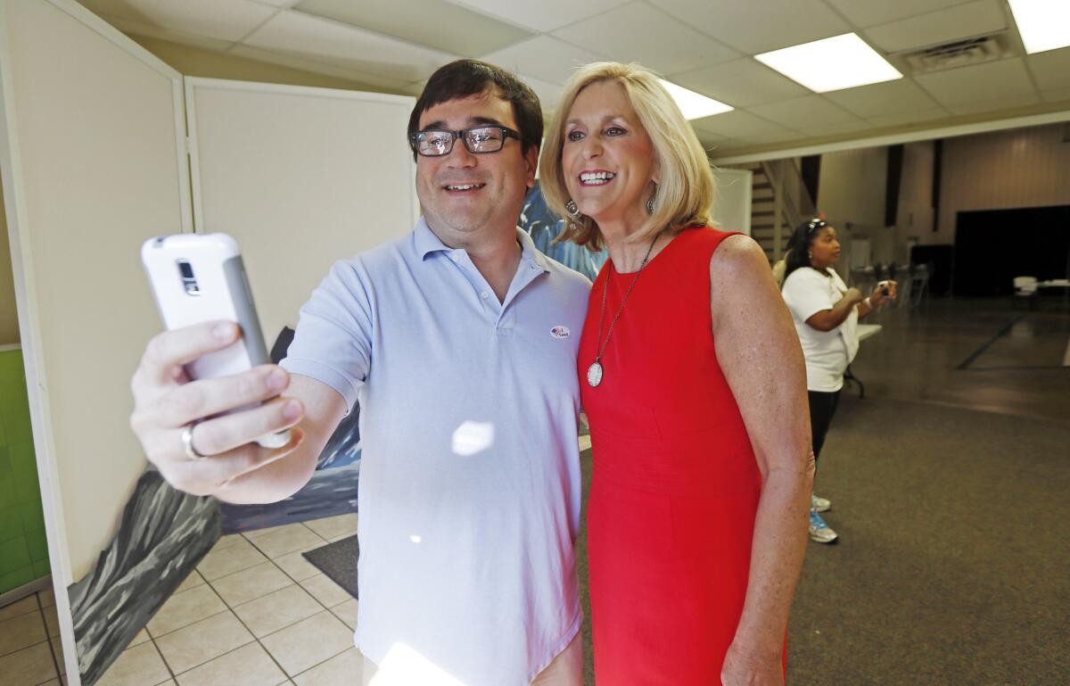 Morgan Bondurant uses his smartphone to take a selfie of himself and state Treasurer Lynn Fitch as they exit the voting precinct after voting in Madison, Miss., on Aug. 4.
