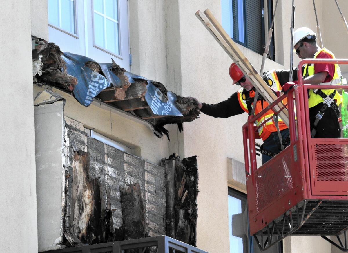Construction crews remove pieces of a balcony that collapsed in Berkeley, exposing what appears to be dry-rot lumber. The collapse killed six people and injured seven a few blocks from UC Berkeley.