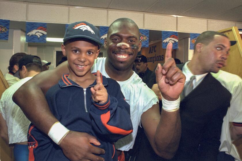**ONE TIME USE ONLY** Denver Broncos running back Anthony Lynn gestures with his son D'Anton in the locker room