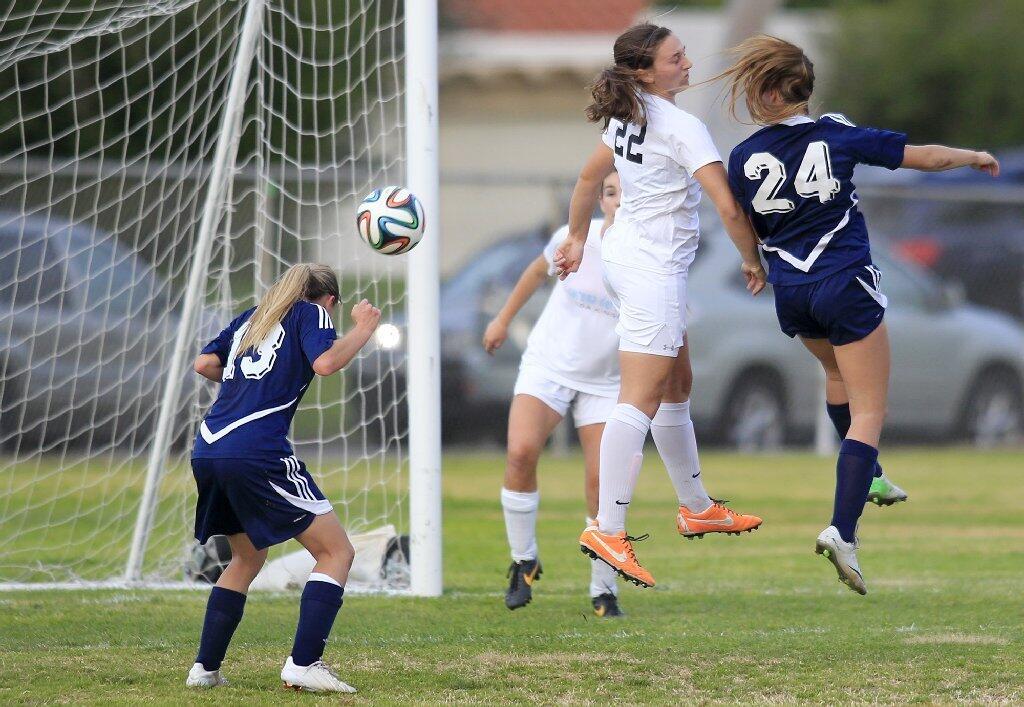 Newport Harbor High's Toni Holland, left, heads in a corner kick during the second half against Corona del Mar in the Battle of the Bay match on Tuesday.