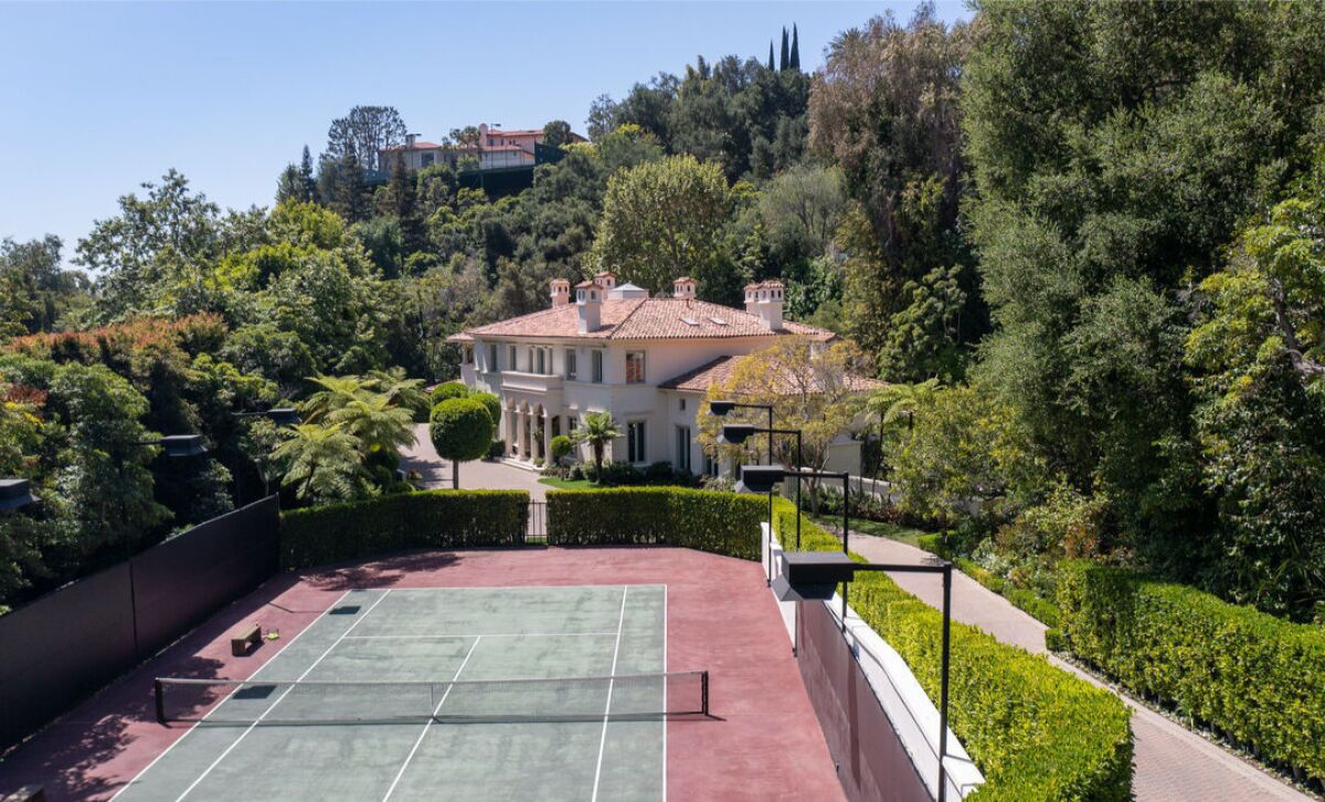 A tennis court with a mansion behind it 