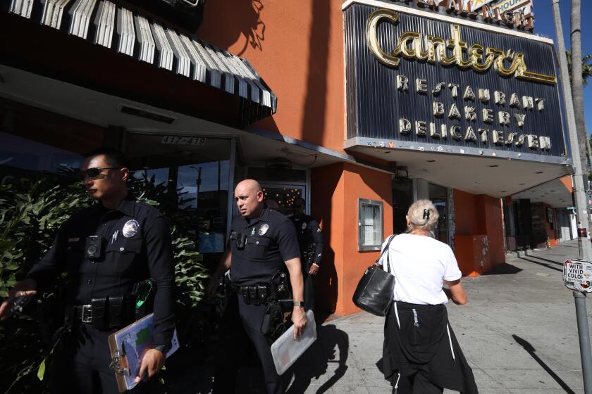 LOS ANGELES, CA - NOVEMBER 1, 2023 - Police walk in front of Canter's Deli where anti-semetic graffiti was left on a wall in the restaurant's parking lot in the Fairfax District in Los Angeles on November 1, 2023. (Genaro Molina / Los Angeles Times)