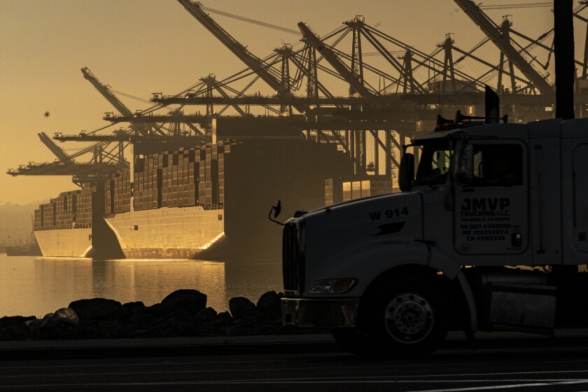 FILE - A truck arrives to pick up a shipping container near vessels moored at Maersk APM Terminals Pacific at the Port of Los Angeles, on Nov. 30, 2021. Contract negotiations between 22,000 workers at 29 West Coast ports and representatives of shipping companies will begin next week with automation and its impact on jobs emerging as a major point of contention amid supply chain issues. (AP Photo/Damian Dovarganes, File)