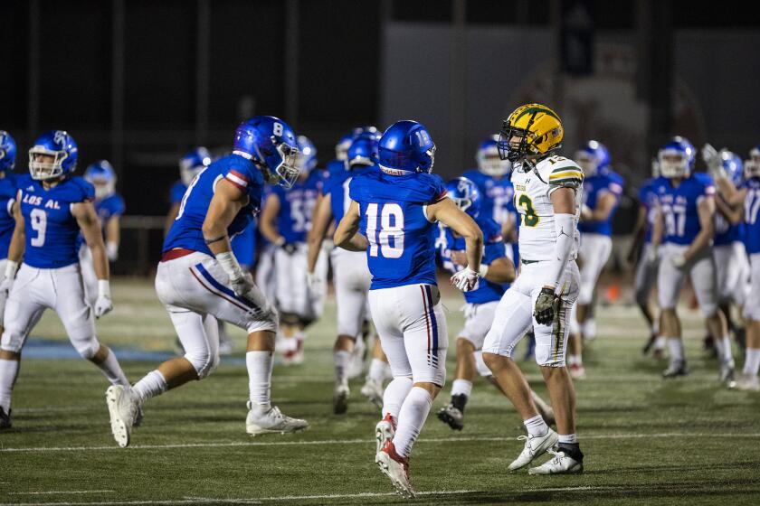 Edison's Tyler Hampton walks off the files as Los Alamitos celebrates a 27-20 win over following a Sunset League on Friday, March 26.