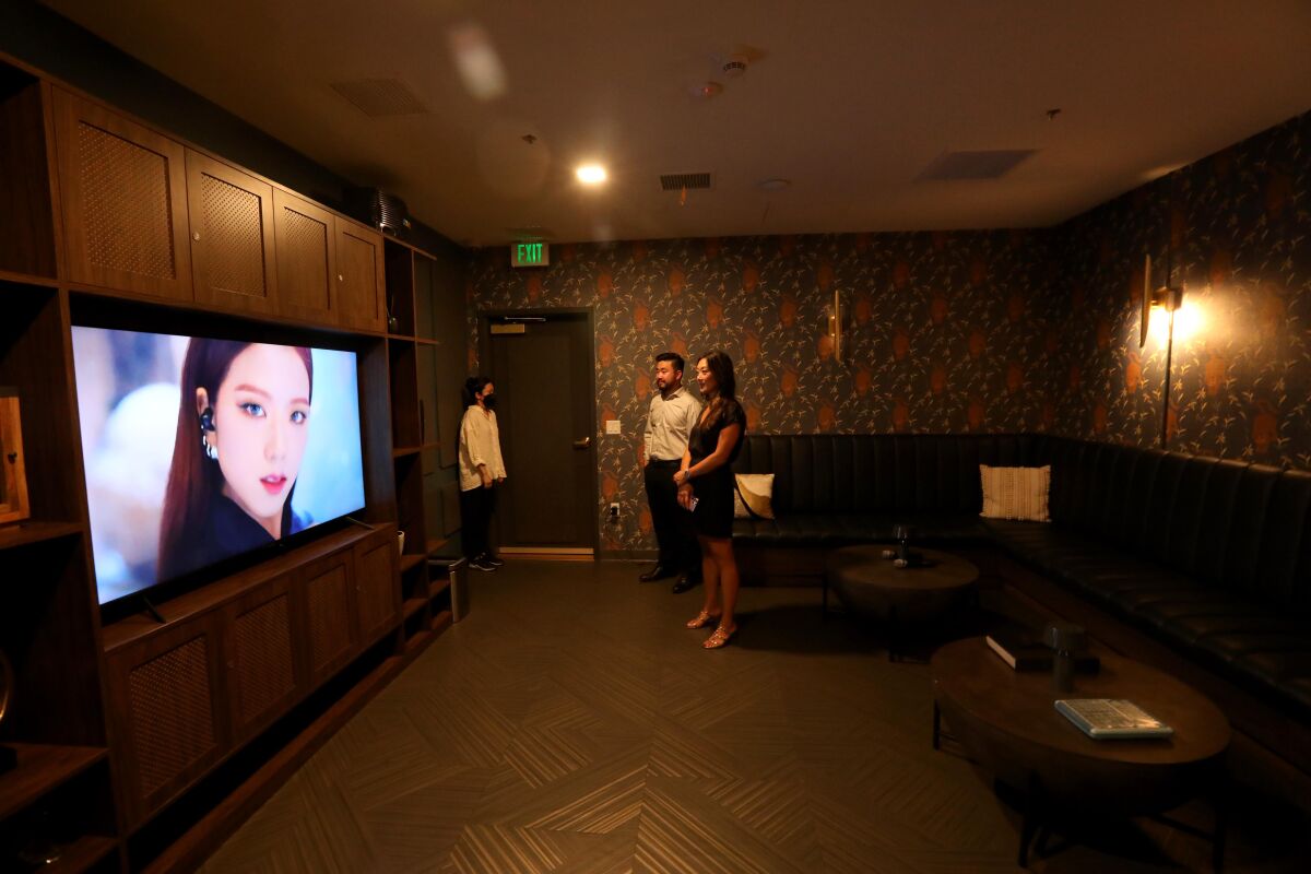 A man and woman watch a television screen in a large room.