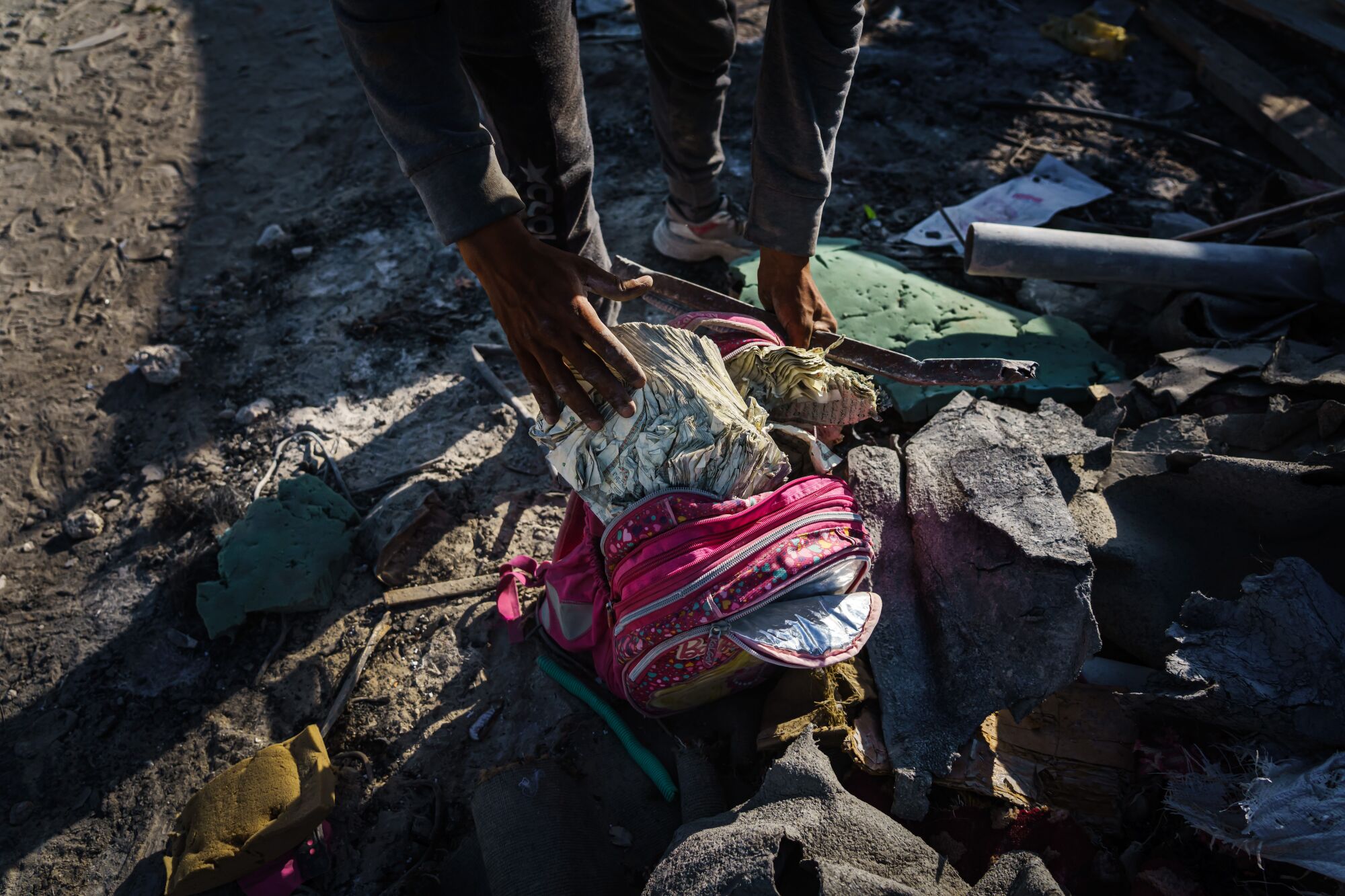 A child's pink school backpack in rubble  