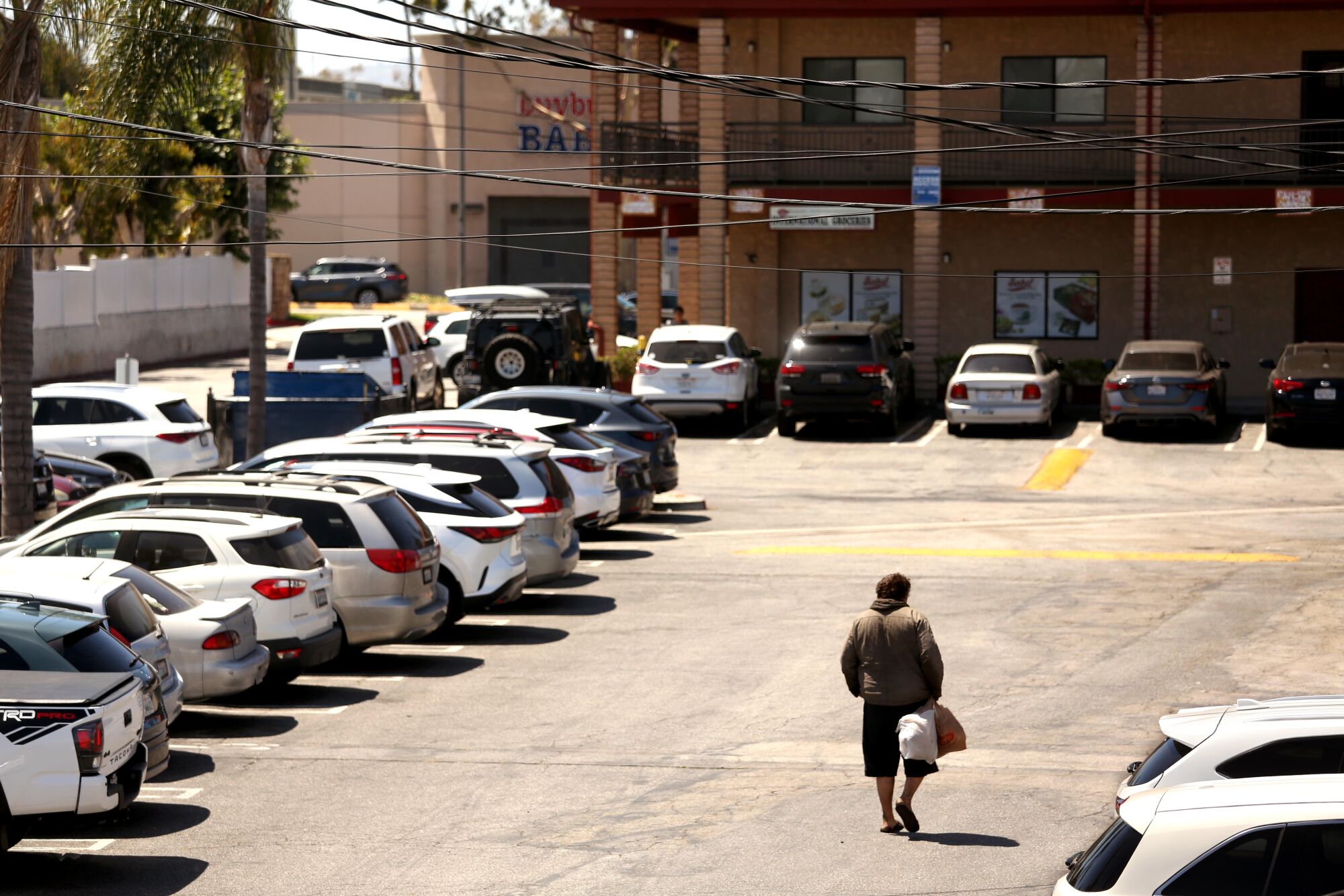 Andrew Truelove carries his only belongings in plastic bags while walking through a parking lot in Torrance.