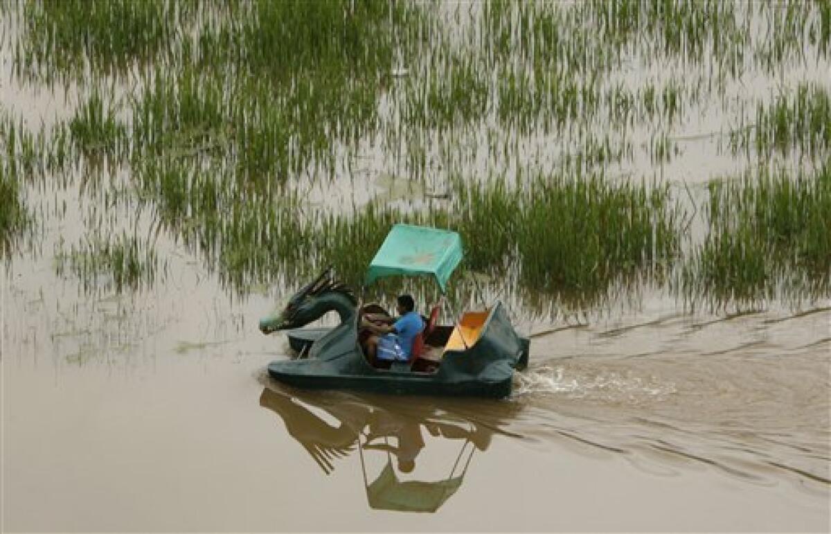 A man rows a boat over a flooded wheat field after the Huatanay river overflowed in Cuzco, Peru, Wednesday, Jan. 27, 2010. Heavy rains and mudslides in Peru have blocked the train route to the ancient Inca citadel of Macchu Picchu, leaving nearly 2,000 tourists stranded.(AP Photo/Martin Mejia)