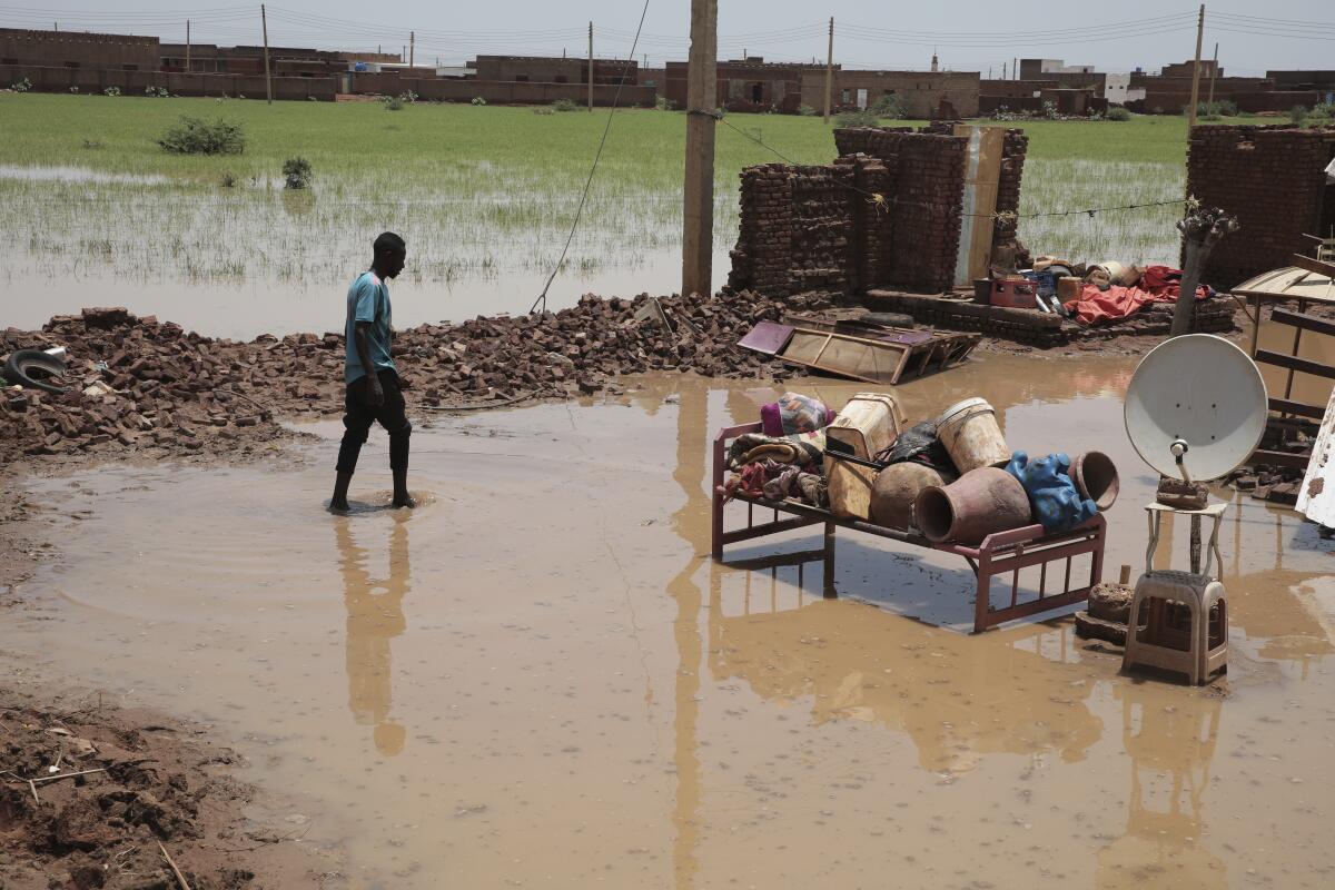 FILE - A man walks in water near the remains of his house after flooding in the village of Aboud in the El-Manaqil district of the Al-Jazirah province, southeast of Khartoum, Sudan, August 23, 2022. A Sudanese official said Wednesday, Aug. 31, 2022, that flash floods triggered by heavy monsoon rains across much of Sudan have killed at least 100 people and injured at least 96 others since the start of the rainy season in May. The United Nations says at least 258,000 people have been affected by floods in 15 of Sudan’s 18 provinces. (AP Photo/Marwan Ali, File)