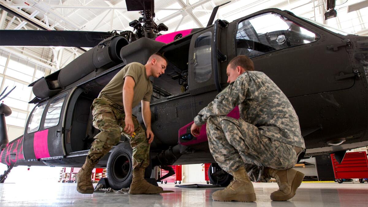Spc. Jesse Lambert, left, and Spc. Daniel Cooper work on a California National Guard UH-60 Black Hawk helicopter that assisted in fighting fires in Ventura County.