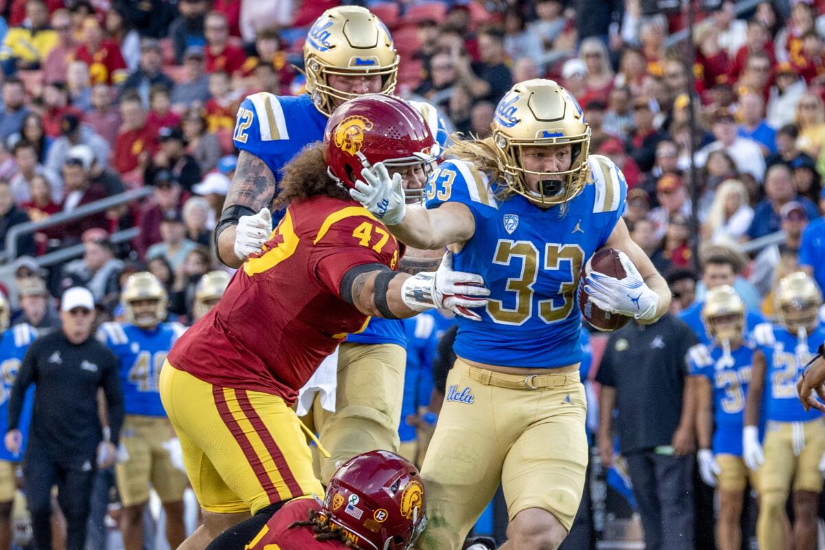 El corredor de UCLA, Carson Steele, se libera de los intentos de tackle de Stanley Ta'ufo'ou y Mason Cobb de USC.